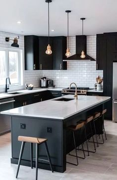 a large kitchen with black cabinets and white counter tops, an island in the middle is surrounded by bar stools