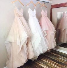 three dresses hanging on a rack in front of a mirror