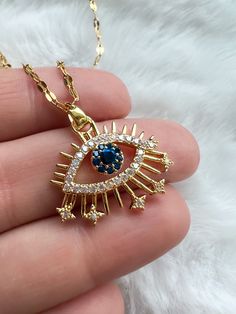 Introducing Our Enchanting Evil Eye Pendant - A Glimmering Guardian of Elegance, Durability, and Hypoallergenic. Our Evil Eye Pendant is a mesmerizing creation, adorned with a stunning array of pave Blue and White Cubic Zirconias. It gracefully dangles from a 16-18 inch adjustable chain, expertly crafted in 18K Gold plated Stainless Steel. This pendant is more than just an accessory; it's a symbol of protection and style combined. Crafted from premium materials, it not only captures hearts and wards off negative energy but is also hypoallergenic. Stainless steel's durability ensures it remains radiant, resisting tarnish and the effects of water exposure, making it the perfect choice for those with sensitive skin. Luxury Blue Necklaces With Diamond Eyes, Evil Eye Necklace With Crystal, Luxury Diamond Evil Eye Jewelry, Luxury Diamond Eyes Necklaces For Women, Luxury Cubic Zirconia Evil Eye Jewelry, Melissa Butler, Evil Eye Crystal, Crystal Eye, Eye Pendant