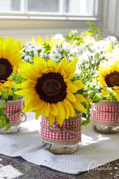 sunflowers and daisies are in mason jars on a table with plaid ribbon