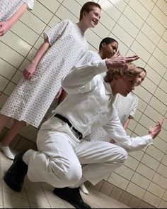 a group of people standing in front of a bathroom mirror with one person kneeling on the floor