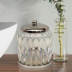 a glass jar sitting on top of a wooden table next to a vase filled with flowers