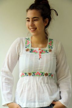 Beautiful vintage 70's Indian white blouse floral embroidered detailing in pink, yellow, blue, green and brown, cotton, long sleeves, five buttons down the bodice, high waist with a belt tied at the back for an adjustable fit, original tag intact, aside from minor signs of wear, including ultra-faint amber marking under the arms, otherwise good vintage condition clean, ready to wear.**Model is 5'8" and a size S/M for reference ** tag size: MApproximate size: S  - Please refer to the measurements Spring Long Sleeve Blouse With Yoke Detail, Fitted Folk Style Long Sleeve Tops, White Long Sleeve Blouse With Yoke Detail, White Long Sleeve Blouse With Yoke, Spring Long Sleeve Top With Yoke Detail, Spring Long Sleeve Top With Yoke, Cotton Long Sleeve Blouse With Yoke Detail, Long Sleeve Cotton Blouse With Yoke Detail, Long Sleeve Cotton Blouse With Yoke