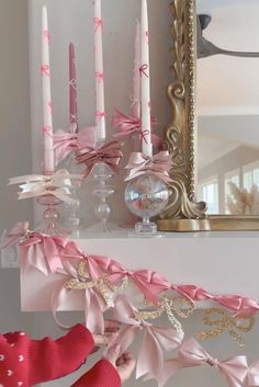 pink candles are sitting on a mantle in front of a mirror and other decor items