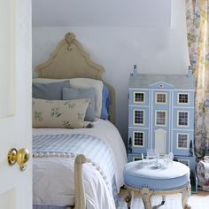 a blue doll house sitting next to a bed in a bedroom