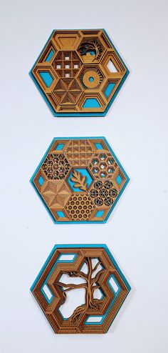 three pieces of art made out of wood on a white surface with blue and brown designs