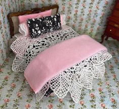 a dollhouse bed with pink and black bedspread, pillows and pillowcases