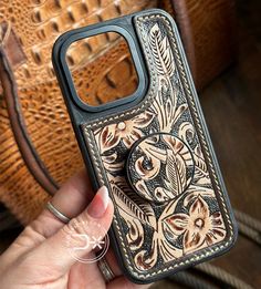 a hand holding a cell phone case with an intricate design on it's side