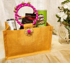 a basket filled with snacks and drinks on top of a table next to a vase