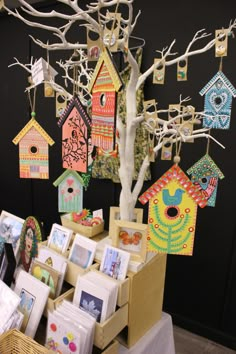 a table topped with lots of cards next to a tree filled with pictures and bird houses