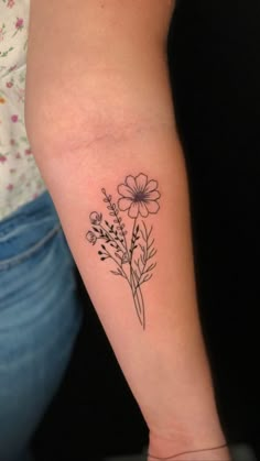 a woman's arm with a flower tattoo on the left side of her arm