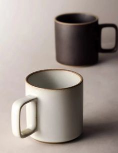 two coffee mugs sitting next to each other on a table