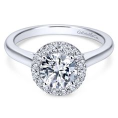 a white gold halo style engagement ring with round diamonds on the shans and shoulders