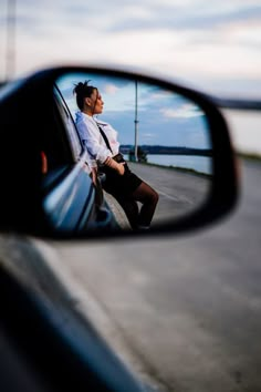 a woman is sitting in the side mirror of a car