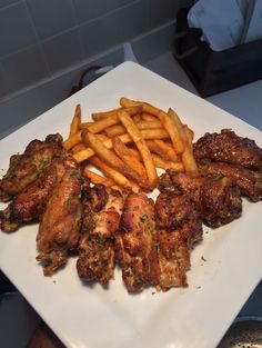 chicken wings and french fries on a white plate