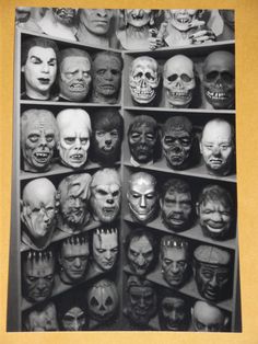 an old black and white photo with many different masks on display in a bookcase