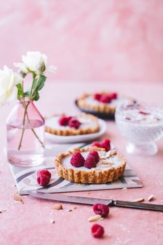 three small desserts with raspberries and almonds on a pink tablecloth