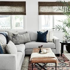 a living room filled with furniture and pillows on top of a rug next to a window