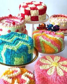 there are many cakes on the table with frosting and icing designs in different colors