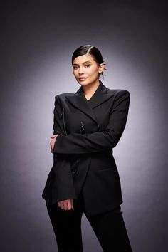 a woman in a black jacket and pants posing for the camera with her arms crossed