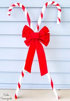 two candy canes tied together with red and white ribbon on the side of a house