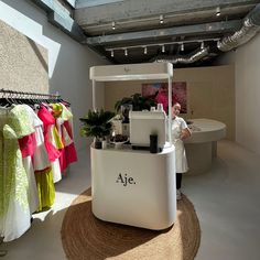 a man standing in front of a counter with clothing on it and hanging from the ceiling