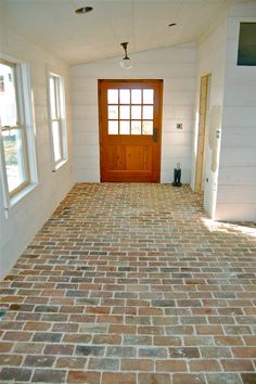 an empty room with brick flooring and a door in the center is seen here