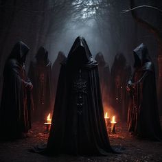 some people in hooded clothing standing around with candles