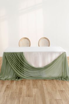 an empty table with two chairs and a green cloth draped over it on a wooden floor