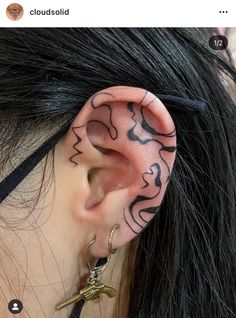 a woman with tattoos on her ear and behind the ear is a pair of scissors