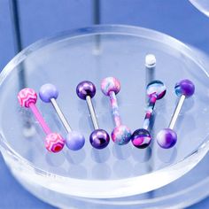 there are many different colored balls in the glass holder on the table and one is pink, purple, and blue