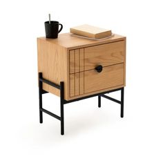 a wooden cabinet with two drawers and a book on top, next to a coffee cup