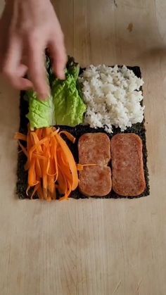 someone is cutting up some food on top of a wooden table with carrots, lettuce and other vegetables