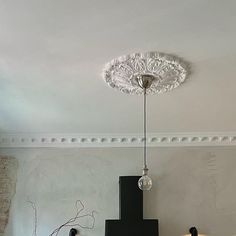 a lamp that is hanging from the ceiling in a room with white walls and flooring