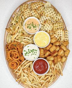 a platter filled with fries, dips and sauces on top of it