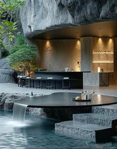 an outdoor kitchen with waterfall in the middle and bar on the other side, surrounded by stone steps