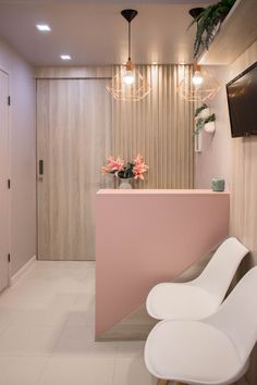 a white chair sitting next to a pink counter in front of a tv mounted on the wall