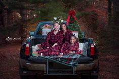 a man and woman sitting in the back of a truck with christmas presents on it