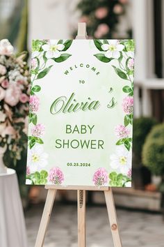 a welcome sign for a baby shower is displayed on an easel in front of flowers