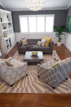 a living room with gray couches and yellow pillows on top of it's rug