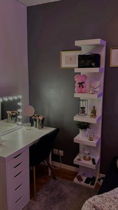 a room with a desk, mirror and shelves on the wall next to a bed