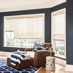 a living room with blue walls and white trim on the window sill is decorated in wicker furniture