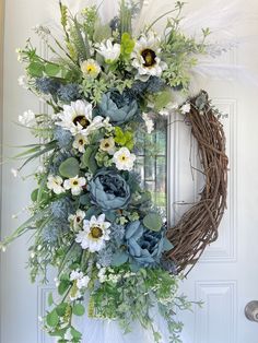 a wreath with flowers and feathers hanging on a door