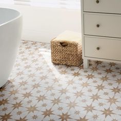 a bathroom with star patterned flooring next to a bathtub and dresser in the corner