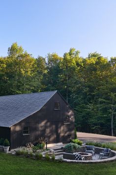 a barn sits in the middle of a lush green field and surrounded by tall trees