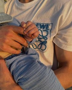 a man holding a small child in his lap while wearing a white t - shirt