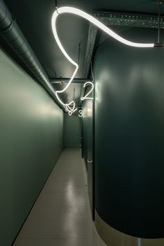 a long hallway with green walls and white lights hanging from the ceiling in front of it