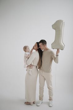 a man and woman holding a balloon in the air with a baby standing next to them