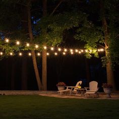 an outdoor patio with string lights strung over it and lawn furniture in the foreground