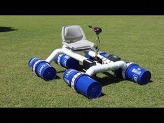 a lawn chair sitting on top of some blue barrels in the middle of a field